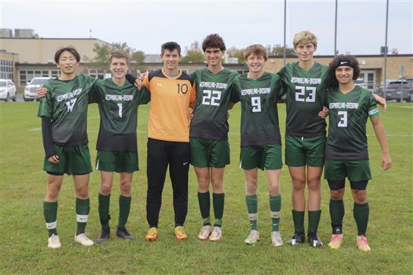 Seniors on soccer team pose with coach on the field